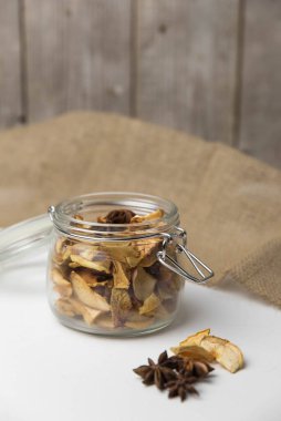 Ev yapımı kavrulmuş, kurutulmuş organik elma dilimleri. Cam kavanozda baharat olan elma cipslerini beyaz arkaplanda izole edilmiş ve metin için kopyalama alanı olan kapat