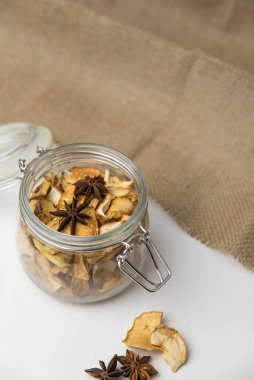 Ev yapımı kavrulmuş, kurutulmuş organik elma dilimleri. Cam kavanozda baharat olan elma cipslerini beyaz arkaplanda izole edilmiş ve metin için kopyalama alanı olan kapat