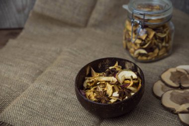 Ev yapımı kavrulmuş, kurutulmuş organik elma dilimleri. Kahverengi ahşap zemin üzerinde baharatlı elma cipslerini metin için kopyalama alanı ile kapat