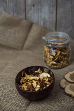 Ev yapımı kavrulmuş, kurutulmuş organik elma dilimleri. Kahverengi ahşap zemin üzerinde baharatlı elma cipslerini metin için kopyalama alanı ile kapat