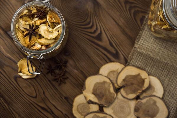 Homemade crispy sun dried organic apple slices. Close up of apple chips with spice in glass jar on brown wooden background with copy space for text
