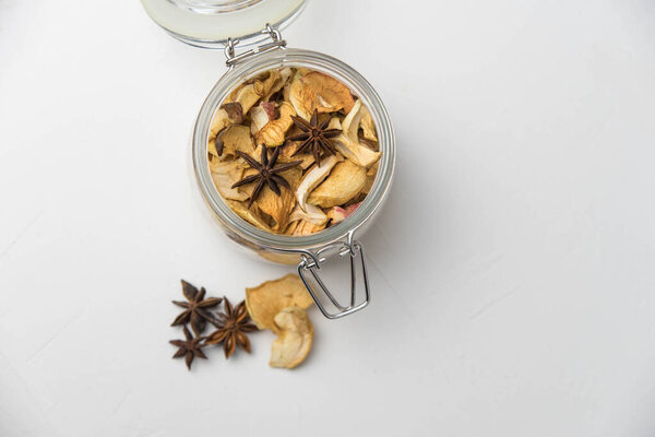 Homemade crispy sun dried organic apple slices. Close up of apple chips with spice in glass jar isolated on white background with copy space for text