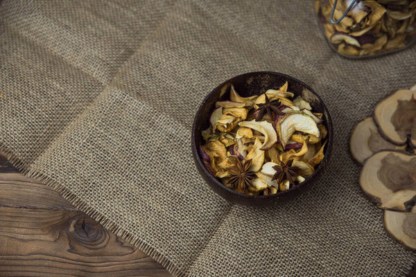 Homemade crispy sun dried organic apple slices. Close up of apple chips with spice in bowl on brown wooden background with copy space for text