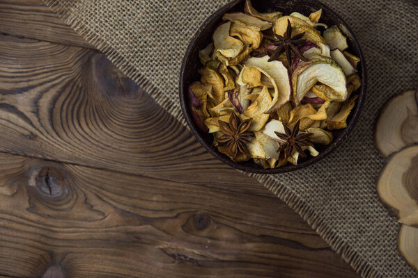 Homemade crispy sun dried organic apple slices. Close up of apple chips with spice in bowl on brown wooden background with copy space for text