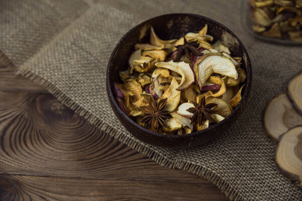 Homemade crispy sun dried organic apple slices. Close up of apple chips with spice in bowl on brown wooden background with copy space for text