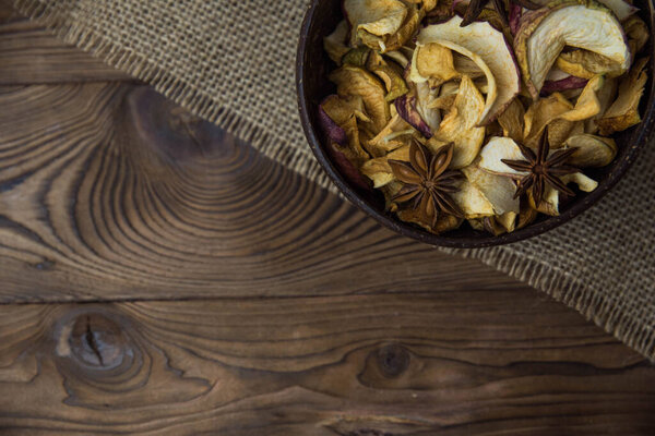 Homemade crispy sun dried organic apple slices. Close up of apple chips with spice in bowl on brown wooden background with copy space for text