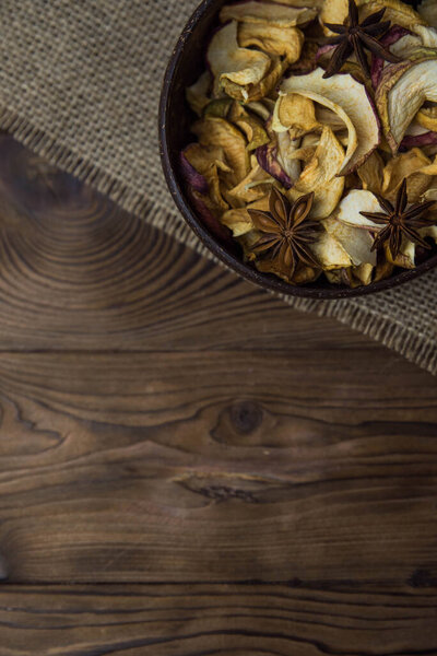 Homemade crispy sun dried organic apple slices. Close up of apple chips with spice in bowl on brown wooden background with copy space for text