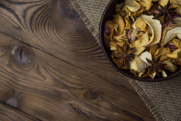 Homemade crispy sun dried organic apple slices. Close up of apple chips with spice in bowl on brown wooden background with copy space for text