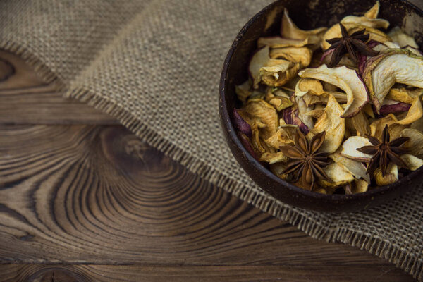 Homemade crispy sun dried organic apple slices. Close up of apple chips with spice in bowl on brown wooden background with copy space for text