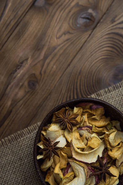 Homemade crispy sun dried organic apple slices. Close up of apple chips with spice in bowl on brown wooden background with copy space for text