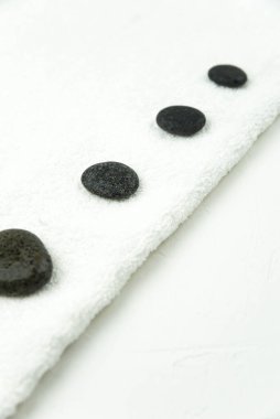 Gri Zen çakıl taşları ve güzellik salonundaki masaj masasında havlu. Sıcak taş masaj seti. Uyum, denge ve meditasyon kavramı, spa, rahatlama, spa tedavisi