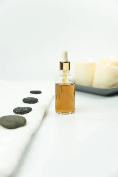 Gri Zen çakıl taşı, havlu ve doğal organik yağ özü serumu güzellik salonundaki masaj masasında. Sıcak taş masaj seti. Uyum, denge ve meditasyon kavramı, spa, rahatlama, spa 