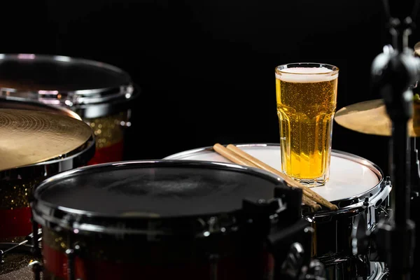 Profesyonel davul setinde bir bardak hafif bira ve tuzlu atıştırmalıklar. Davullar, davullar ve ziller, canlı müzik rock konserinde, kulüp sahnesinde, barda ya da kayıt stüdyosunda. Siyah arkaplan.