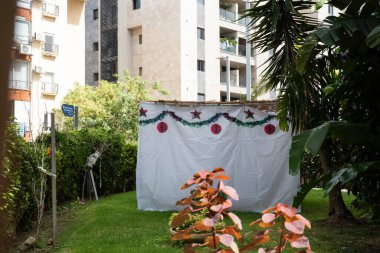 İsrail 'de Yahudi festivali Sukkot. Sokaktaki binanın yanında el yapımı süslemeleri olan geleneksel sukkah.. 