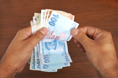          Ahşap arka planda lastik bantlı bir avuç dolusu banknot. Para ve finansal konsept                         