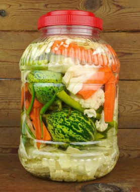 Tahta arka planda izole edilmiş kavanozlarda sebze turşusu..