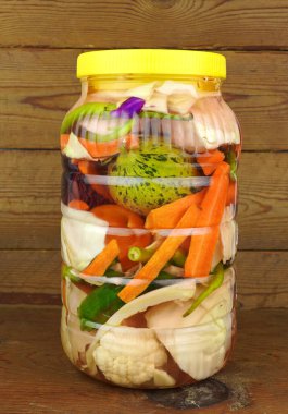 Tahta arka planda izole edilmiş kavanozlarda sebze turşusu..