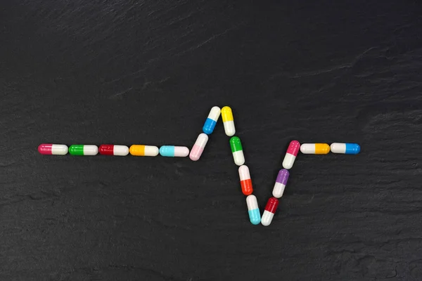 Siyah Arka Planda Renkli Tıbbi Kapsülleri Olan Ekg Grafiği Kavramsal — Stok fotoğraf