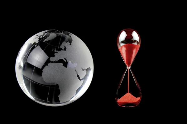 Globo de cristal e ampulheta vermelha sobre fundo preto. Imagem conceitual . — Fotografia de Stock