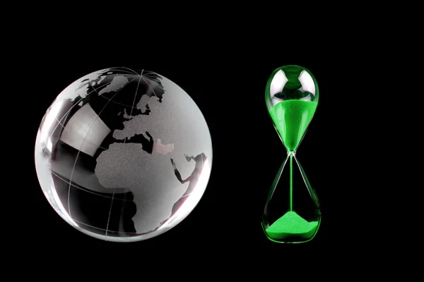 Globe de cristal et sablier vert sur fond noir. Image conceptuelle . — Photo