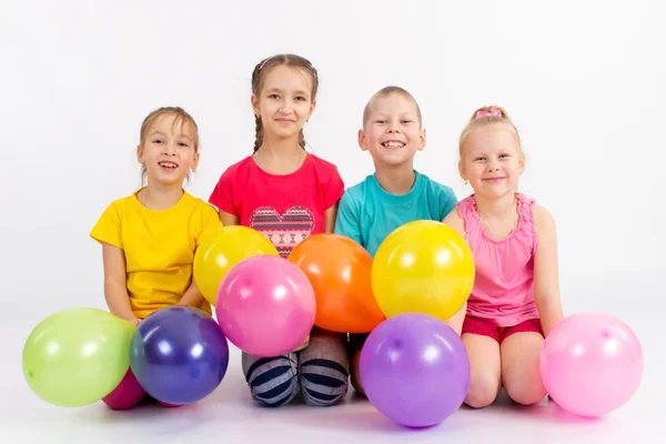 Cuatro niños alegres con globos sobre un fondo blanco — Foto de Stock