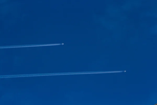 暗く青い空に飛行機雲を残して高高度で飛行 ommercial 飛行機. — ストック写真