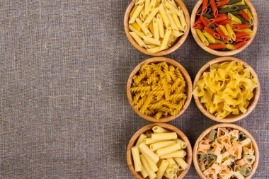 Makarna ahşap arka plan, çuval bezi çanta, bambu kase üzerine çeşitli birleşimleri. diyet ve beslenme kavramı.