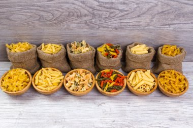 Makarna ahşap arka plan, çuval bezi çanta, bambu kase üzerine çeşitli birleşimleri. diyet ve beslenme kavramı.