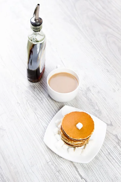 Tasty pancake on a white plate, wooden background, maple syrup — Stock Photo, Image