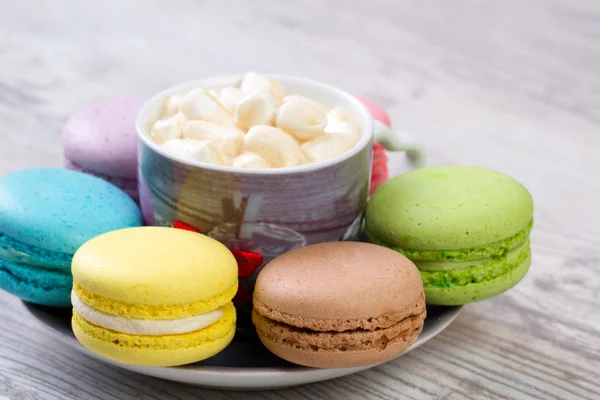 Colección de coloridos macarrones franceses están uno al lado del otro alrededor de los platos — Foto de Stock