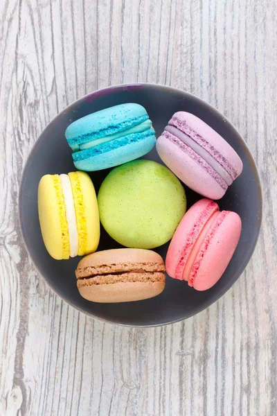 Collection of colorful French macarons are next to each other around the plates, top view — Stock Photo, Image