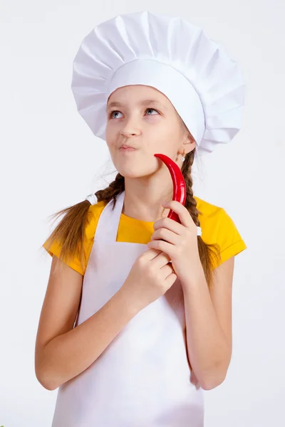 Meisje in een bedrijf in de buurt van het gezicht rode chilipeper, schort geïsoleerd achtergrond — Stockfoto