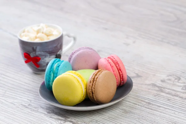 Collection of colorful French macarons are next to each other around the plates — Stock Photo, Image