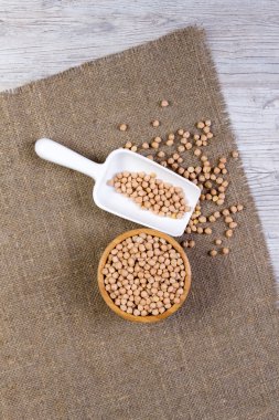 Beyaz ahşap zemin üzerinde bir kürek ile bir bambu kapta ceviz nohut