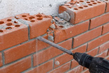 İnşaatçı bir araçla duvarın tuğla işçiliğini kırar.