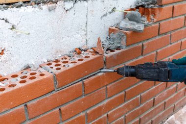 İnşaatçı bir araçla duvarın tuğla işçiliğini kırar.