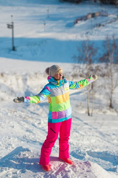 Girl in a ski suit standing stretched in different directions hands and eyes closed — Stock Photo, Image