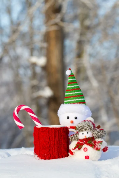 Dos muñeco de nieve con taza roja y dulces — Foto de Stock