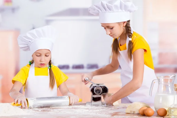 Два маленьких кухаря розтягують тісто — стокове фото