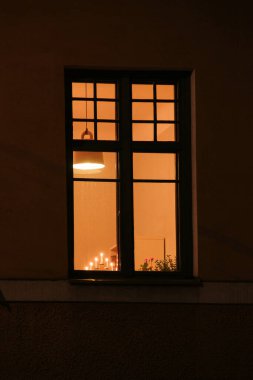 Pencere kenarında yedi mum olan dekoratif bir lambayla aydınlatılmış bir pencere.
