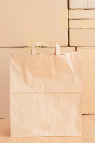 kraft paper bag with handles on the background of cardboard boxes with purchases