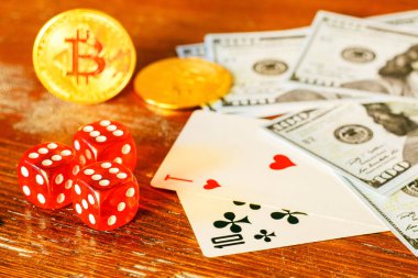 Tahta bir masaya saçılmış: iskambil kartları, zarlar, dolar banknotları ve bitcoin 'ler