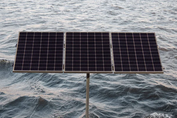 海の波を背景に海岸に設置された代替電源である太陽電池パネル — ストック写真