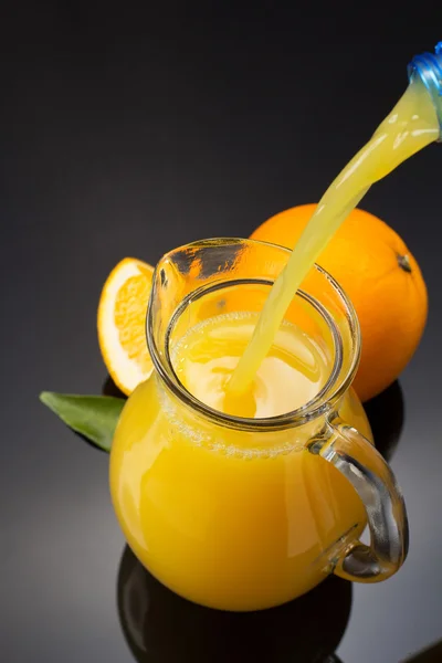 Glaskrug und Orangensaft auf Schwarz — Stockfoto