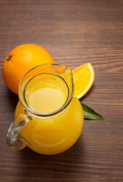 Glass pitcher and orange juice on wood — Stock Photo, Image