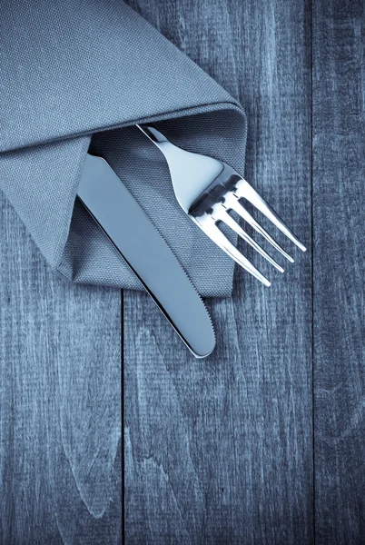 Cuchillo y tenedor en la servilleta en madera — Foto de Stock