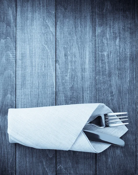 Knife and fork at napkin on wood — Stock Photo, Image