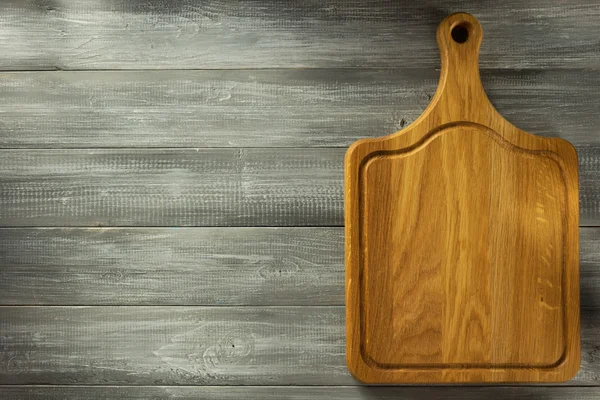 Cutting board at wooden table — Stock Photo, Image