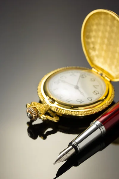 Pocket watch och bläck penna på svart — Stockfoto