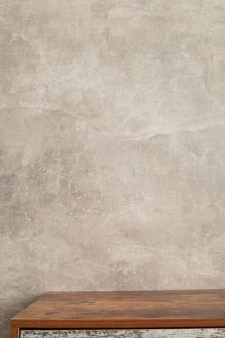 Gri duvar arkaplan dokusu yüzeyinin yanındaki ahşap masa